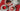 set of 3 white tea plates with strawberry desserts with a white pitcher on a red place mat