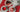 set of 3 white tea plates with strawberry desserts with a white pitcher on a red place mat