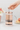 Person using a pink loose leaf teaFrench press with flowers and macarons in the background
