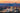 A scenic photograph of Asheville, NC from above with the blue ridge mountains and a colorful sky at sunset behind it.