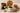 A neutral-toned tea scene features a steaming cup of amber tea in a speckled white cup and saucer, surrounded by stacked black stones, fresh mint, loose-leaf tea in a wooden bowl, cinnamon sticks, turmeric root, and dried lavender on a beige surface.