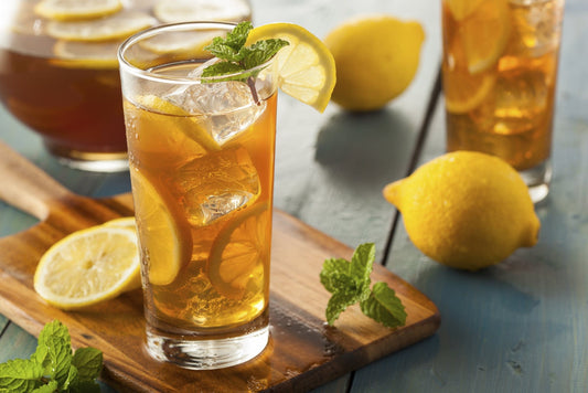 A glass of iced tea with mint and lemon around it Full Moon Tea Company loose leaf tea.