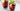 two red iced beverages with berries and herbs in short glasses