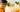 glass cup with orange beverage and ice topped with a peach slice and mint