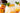 glass cup with orange beverage and ice topped with a peach slice and mint