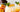 glass cup with orange beverage and ice topped with a peach slice and mint
