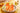 On a white round tray, two tall glasses of peachy colored tea with ice, fruit, and garnishes in the sunlight.