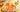 On a white round tray, two tall glasses of peachy colored tea with ice, fruit, and garnishes in the sunlight.