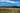 A  panoramic view of a tea farm in South Africa with mountains and a blue sky in the background.