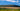 A  panoramic view of a tea farm in South Africa with mountains and a blue sky in the background.
