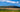 A  panoramic view of a tea farm in South Africa with mountains and a blue sky in the background.