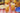 A gingham tablecloth with fried chicken, pasta salad, fruit, plates, and two glasses of iced tea with lemon wedges.