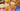 A gingham tablecloth with fried chicken, pasta salad, fruit, plates, and two glasses of iced tea with lemon wedges.