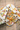 Four boxes of honey sticks on a platter with candy and a plaid tablecloth. 