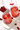 Two glasses of red cherry cocktail with ice and cherries on a white surface