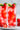 Two glasses of red strawberry lemonade with ice and garnishes on a white plate.