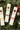 Four packages of 'Bee Inspired' honey sticks on a festive green background with Christmas decorations.