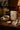 A box of Be Inspired Honey Candy sits on a rustic wooden table next to a ceramic cup of black coffee, a small dish with two candies, and a linen cloth. The scene is warmly lit by a table lamp in the background.