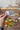 Hand holding a 'Full Moon Tea Co.' sticker in front of a brick wall with a floral arrangement.