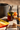 Jar of pumpkin spice honey with a honey dipper and pumpkin-themed items on a wooden surface.