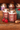 Jars of strawberry creamed honey with strawberries and a honey dipper on a wooden surface.