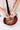 Hands processing raspberries into a blend of tea ingredients over a bowl.