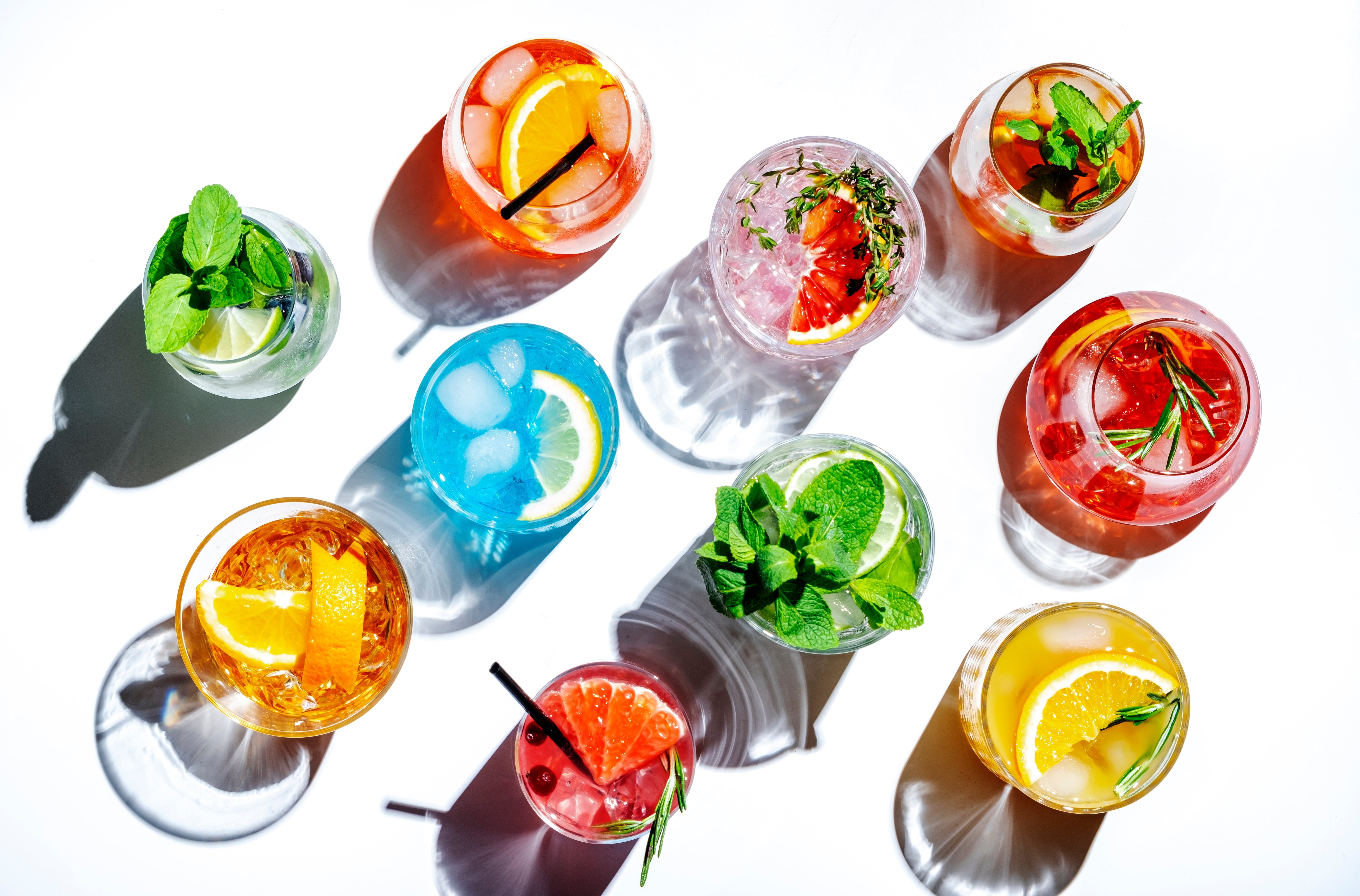 Assorted colorful cocktails with garnishes on a white background